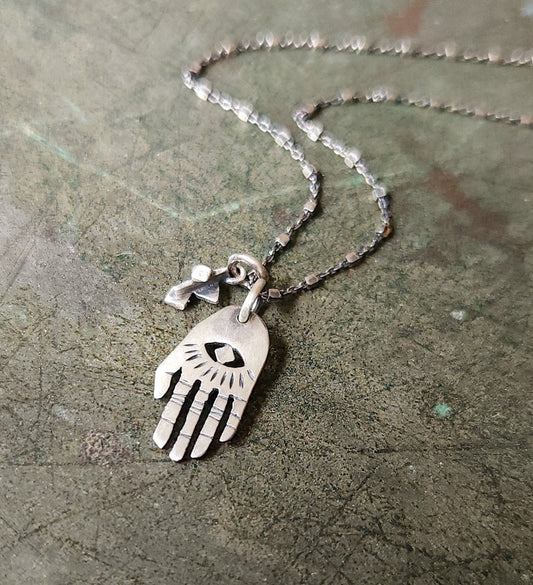 A silver Hamsa necklace with a brushed finish and a chain featuring a pendant with a Hamsa hand design.