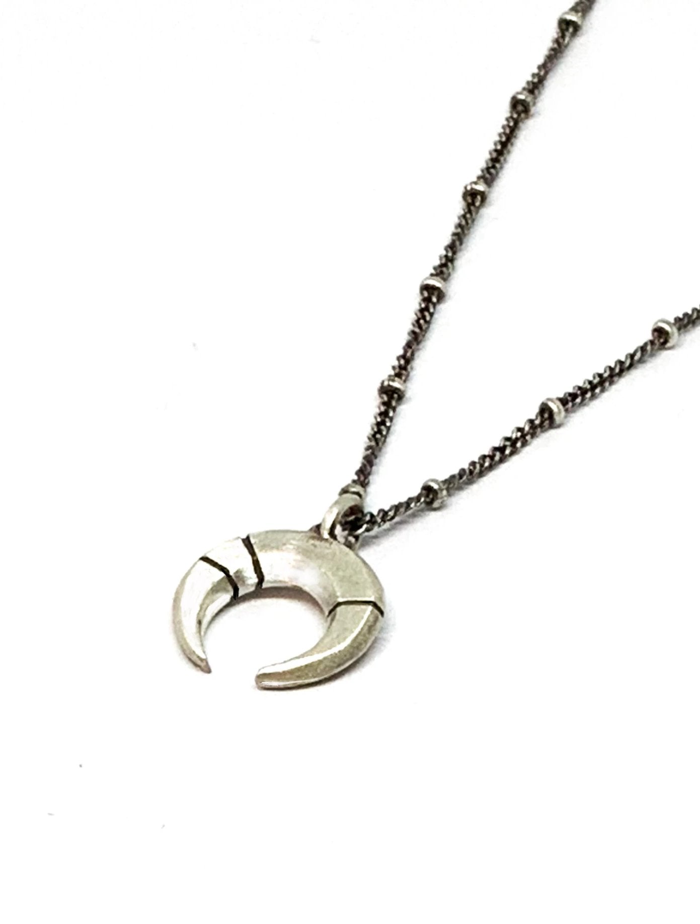 A silver necklace with a crescent-moon pendant and chain.