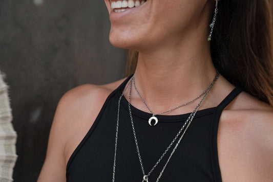 A silver necklace with a crescent-moon pendant and chain.