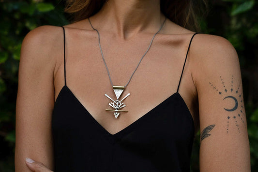 A silver and brass necklace with a geometric pendant, featuring a chain and a series of geometric shaped pendants attached to it.