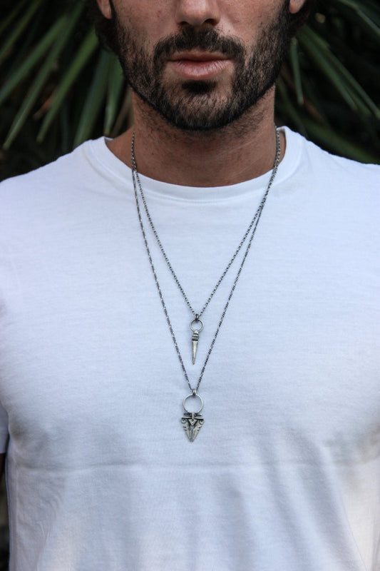 A sterling silver necklace with an oxidized and brushed finish, featuring a pendant with a strength symbol design.