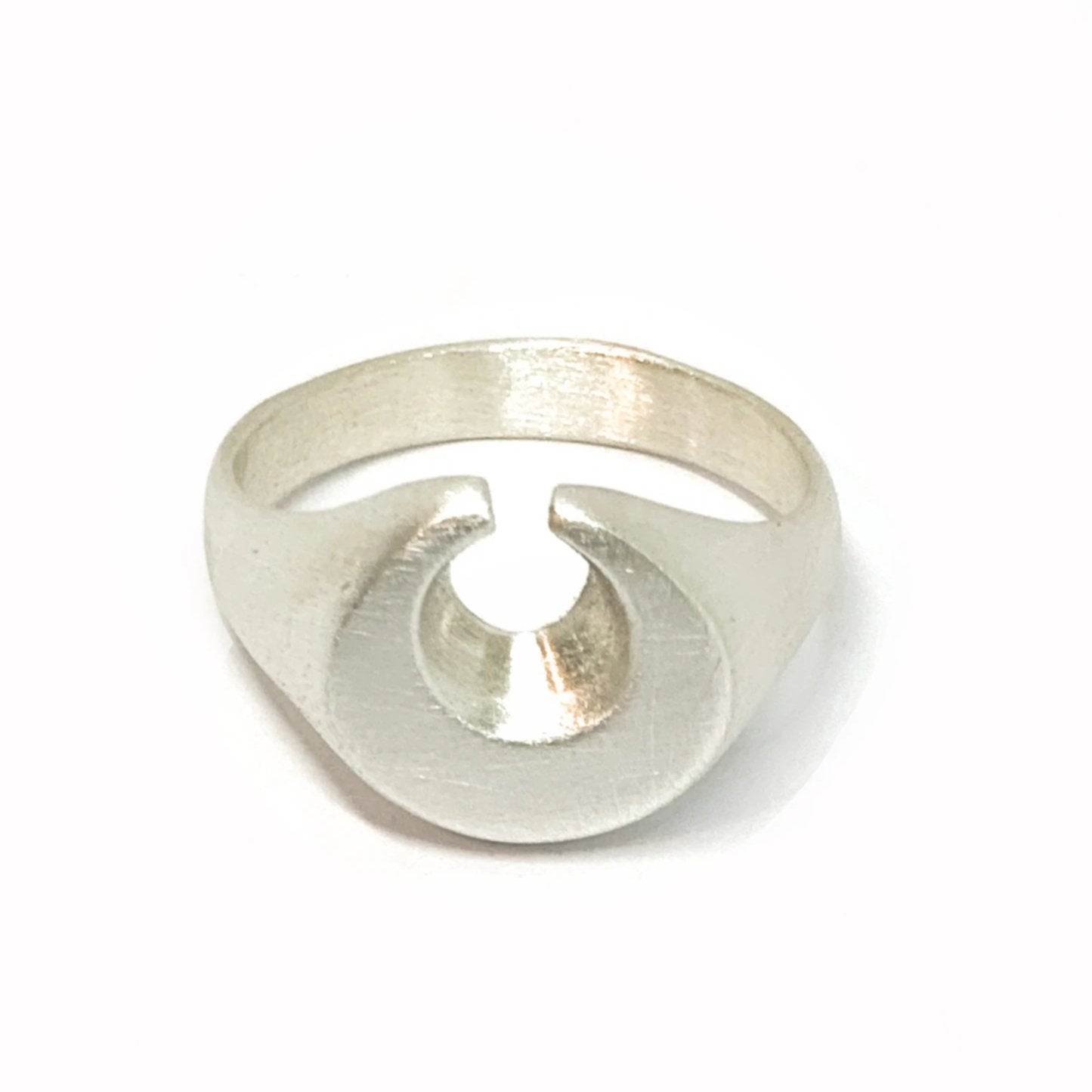 A silver ring featuring a brushed finish, handcrafted in the shape of a moon.