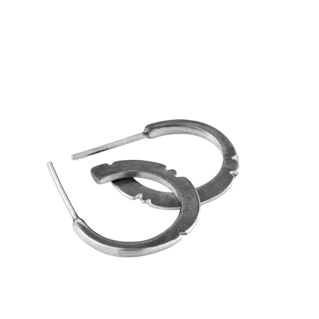 A pair of oxidized silver hoop earrings with a brushed finish, displayed against a white background.