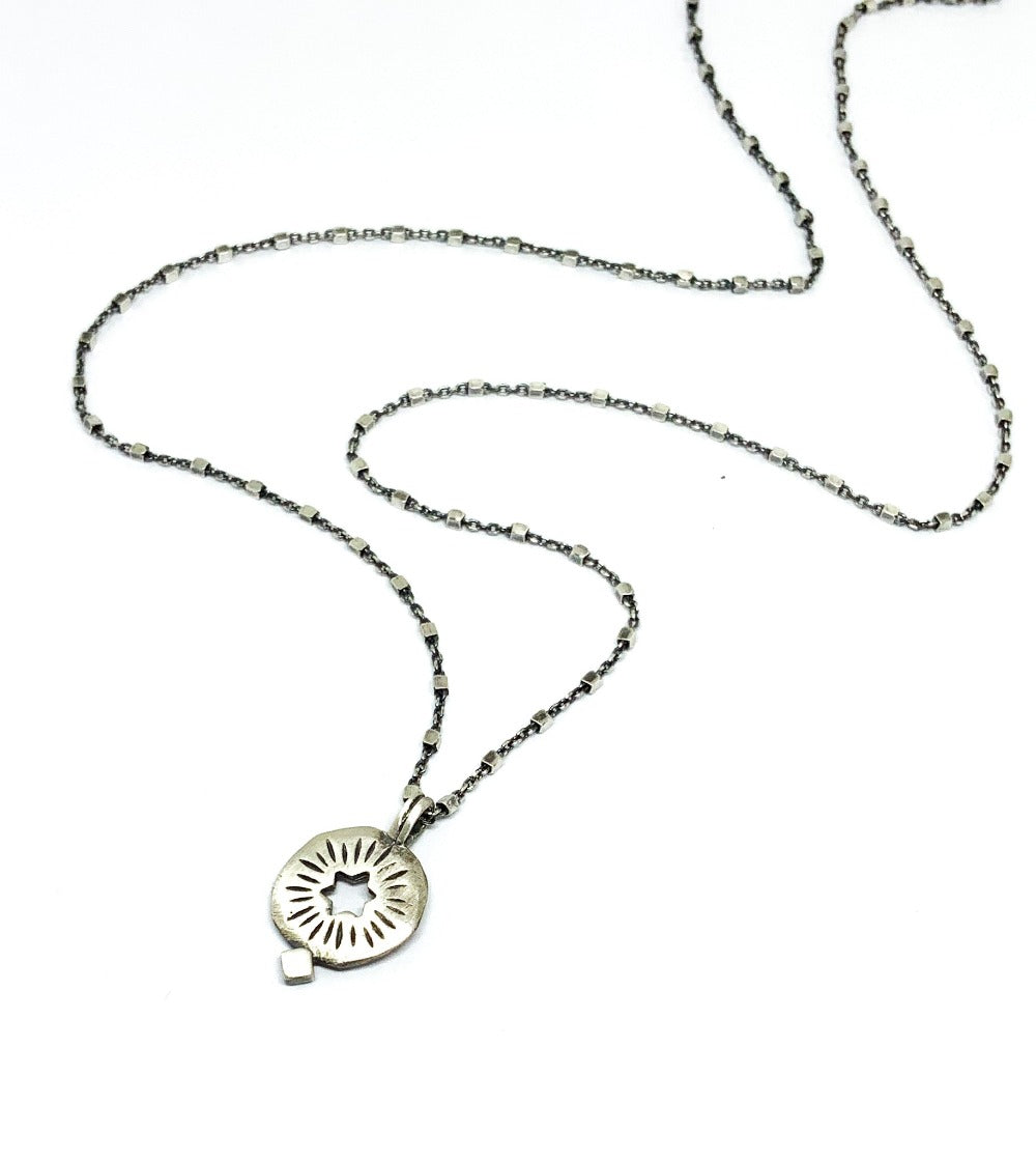 A silver pendant on a chain with a cut out star 