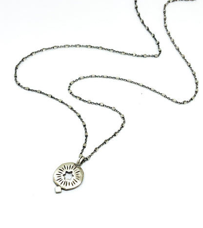 A silver pendant on a chain with a cut out star 