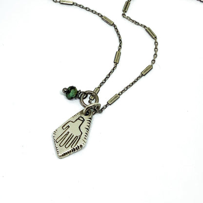 A silver Hamsa necklace with a turquoise stone pendant, featuring a chain and a lobster clasp closure.