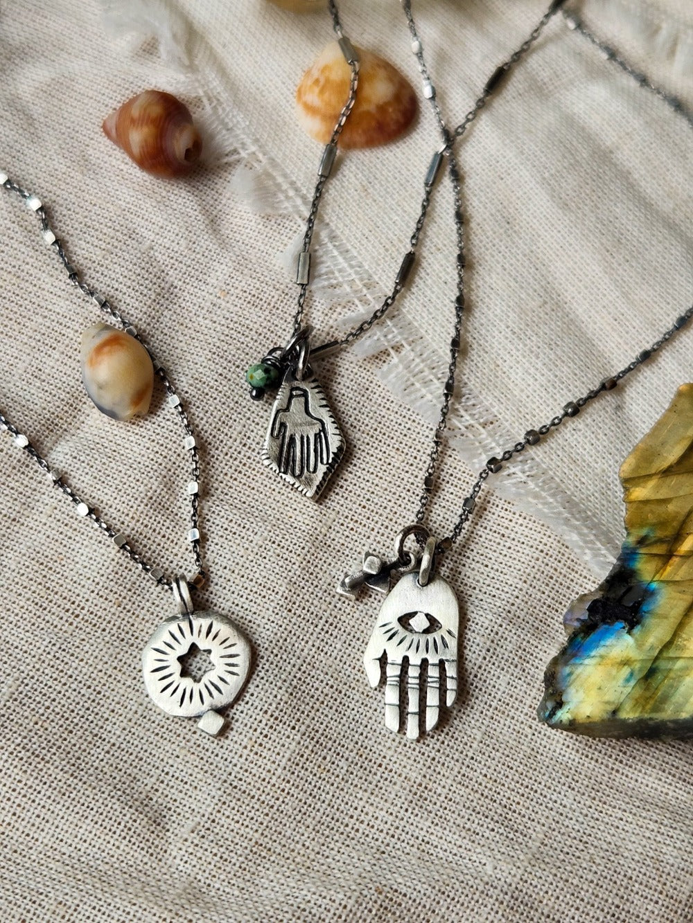 3 silver necklaces: hamsa, circle with hollow star and rombus hamsa