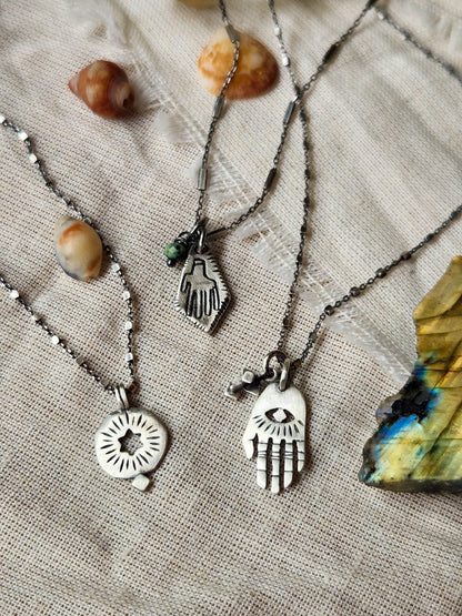 3 silver necklaces: hamsa, circle with hollow star and rombus hamsa