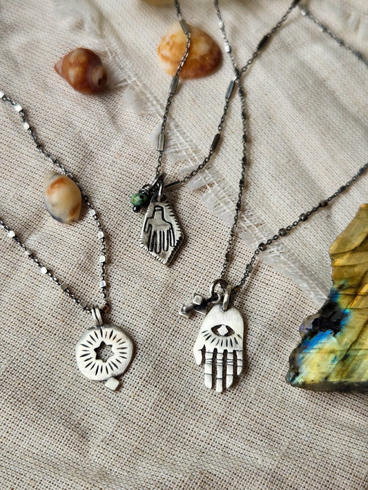 3 silver necklaces: hamsa, circle with hollow star and rombus hamsa