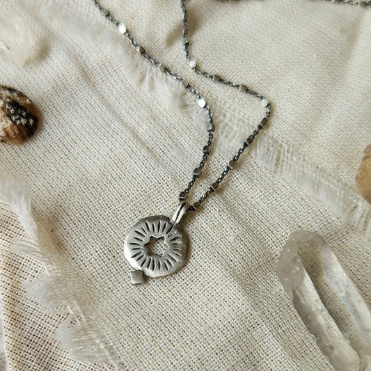 A silver necklace with a rising star of david pendant, displayed on a textured background with a white shimmering object and a small crystal.