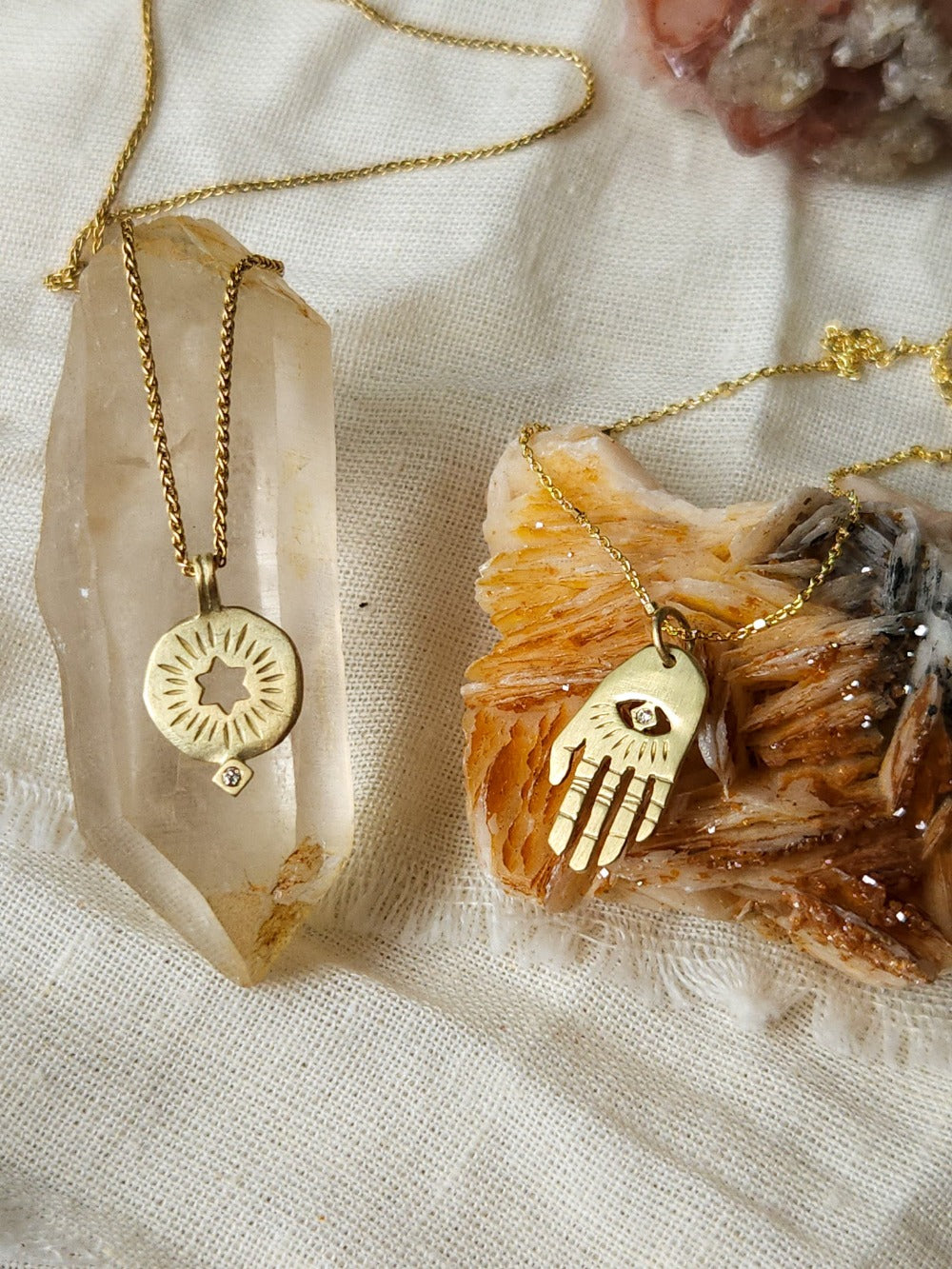 A golden necklace with a white diamond pendant in the shape of a rising star of David, displayed on a lace background with some crystal pieces.