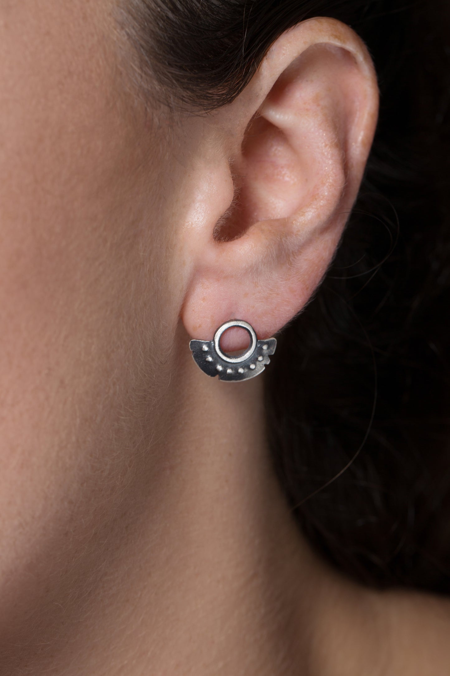 A pair of oxidized sterling silver dotted half moon earrings with a brushed finish