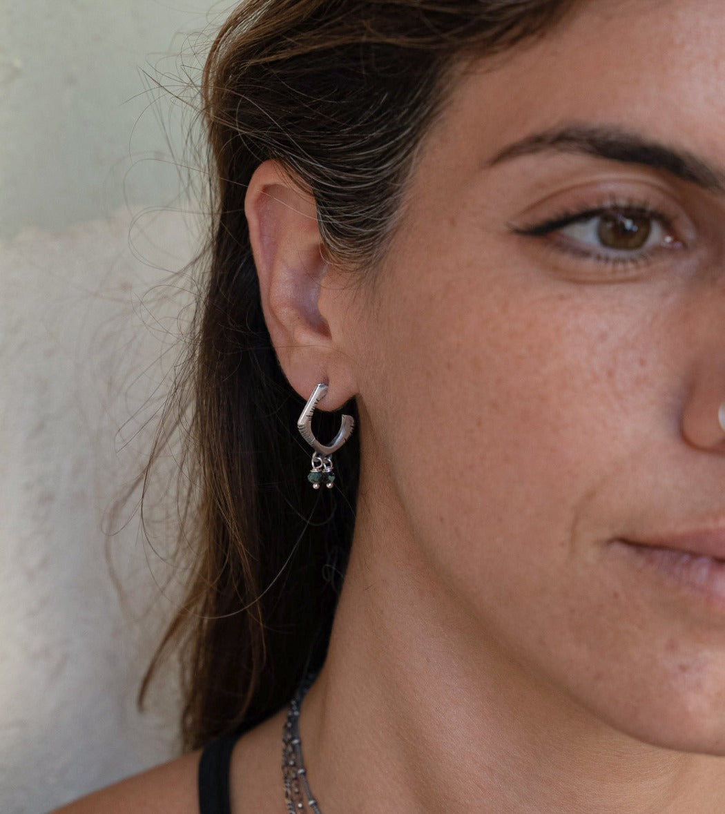 A pair of sterling silver oxidized and brushed finish earrings with turquoise accents and decorative stones.