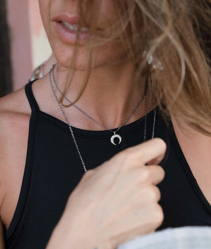 A silver necklace with a crescent-moon pendant and chain.
