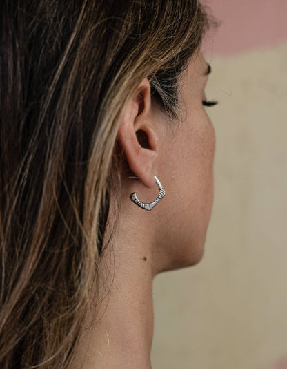 A pair of silver oxidized and brushed finish earrings with a geometric pattern, handcrafted.
