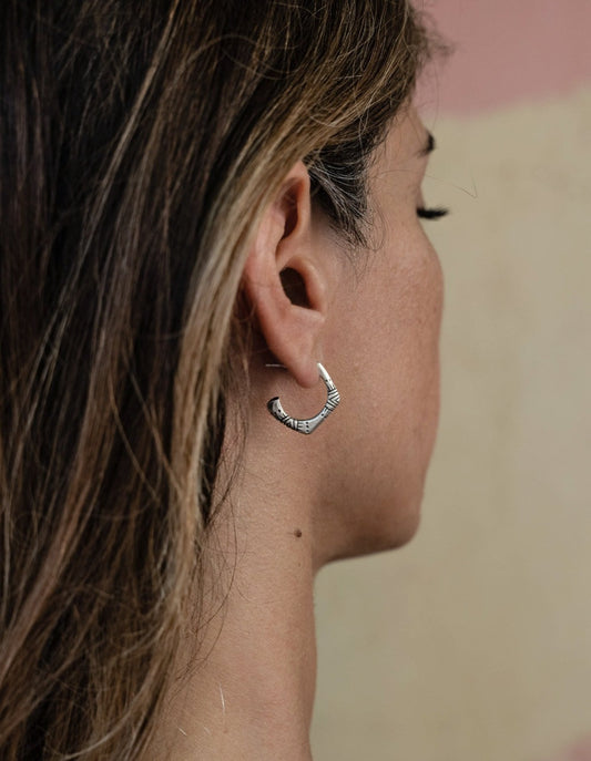 A pair of silver oxidized and brushed finish earrings with a geometric pattern, handcrafted.