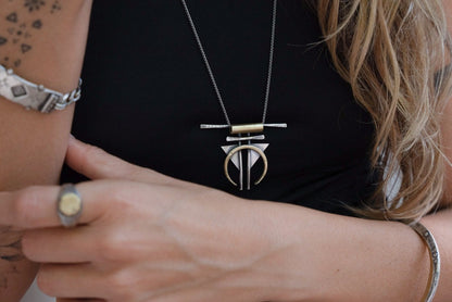 A silver and gold-colored necklace with a geometric pendant, featuring a chain and a series of geometric shaped pendants attached to it.