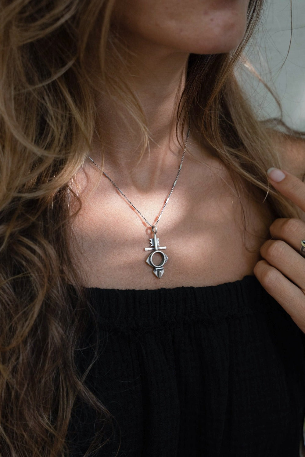 A silver necklace with a geometric-patterned pendant, featuring a combination of Morrocan and Mexican inspiration.