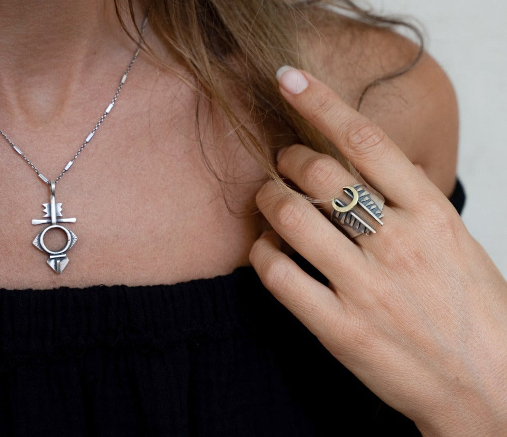 A silver necklace with a geometric-patterned pendant, featuring a combination of Morrocan and Mexican inspiration.