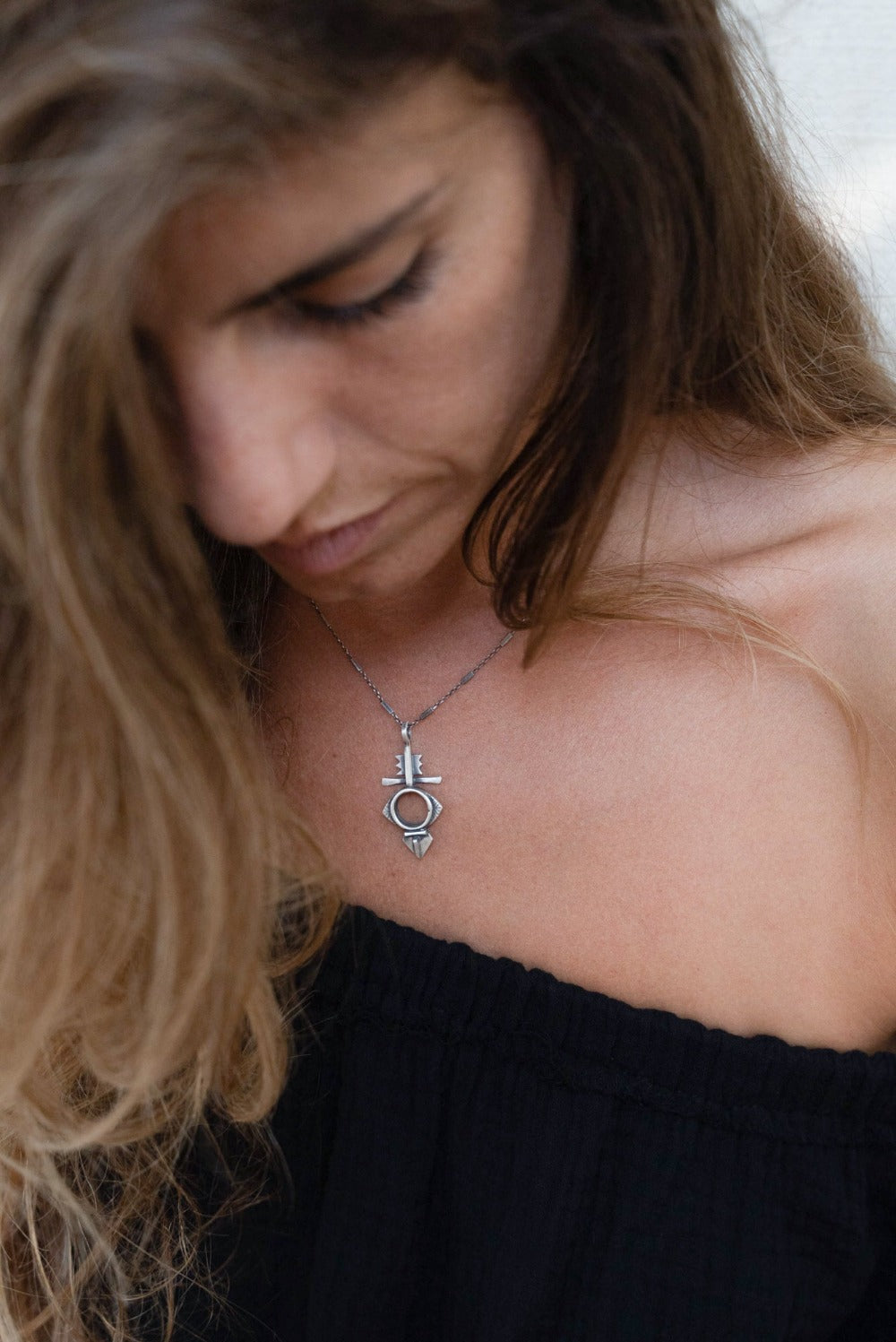 A silver necklace with a geometric-patterned pendant, featuring a combination of Morrocan and Mexican inspiration.