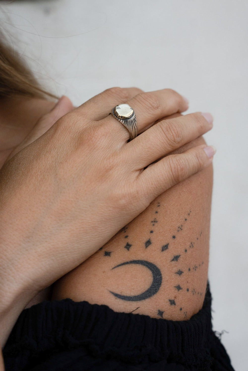 A silver ring with a brushed finish and a central golden brass sun emblem, with engraved patterns around it.