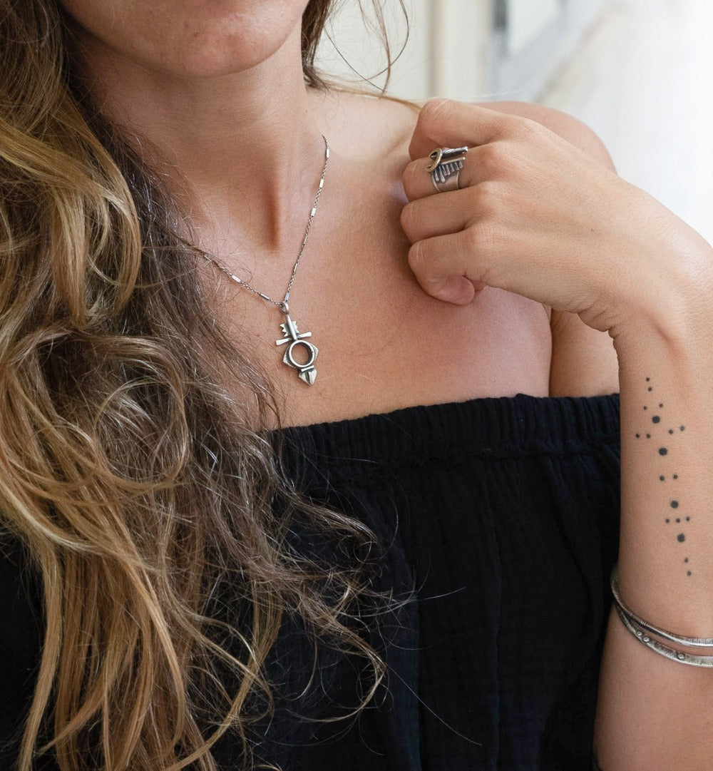 A silver necklace with a geometric-patterned pendant, featuring a combination of Morrocan and Mexican inspiration.