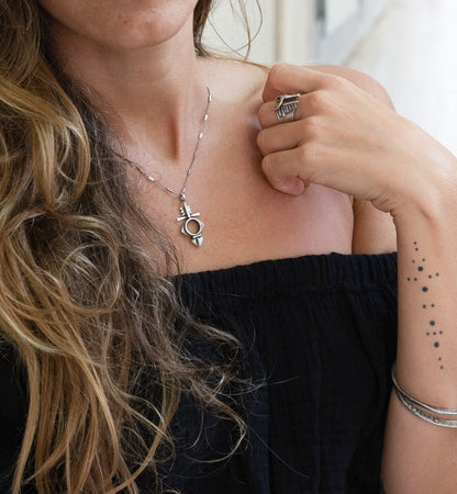 A silver necklace with a geometric-patterned pendant, featuring a combination of Morrocan and Mexican inspiration.