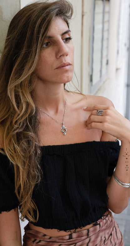 A silver necklace with a geometric-patterned pendant, featuring a combination of Morrocan and Mexican inspiration.