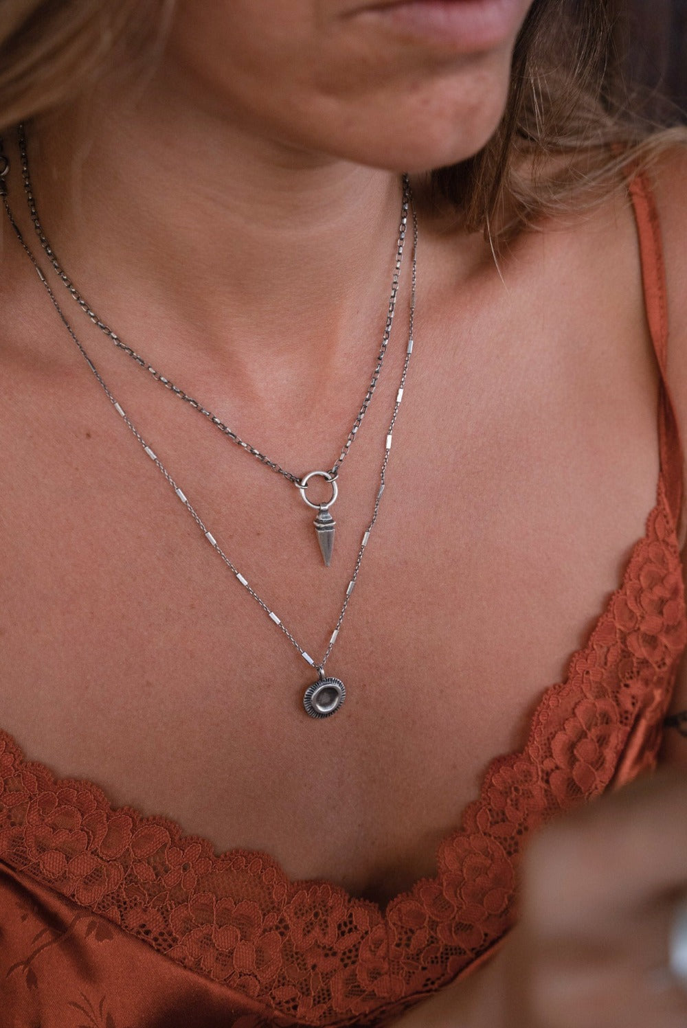 A sterling silver pendulum necklace with a brushed finish and a chain loop at the top.