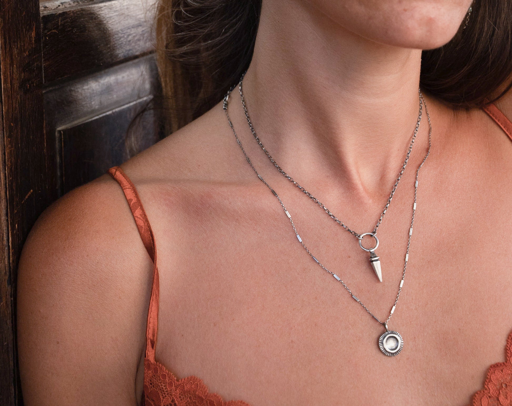 A sterling silver pendulum necklace with a brushed finish and a chain loop at the top.