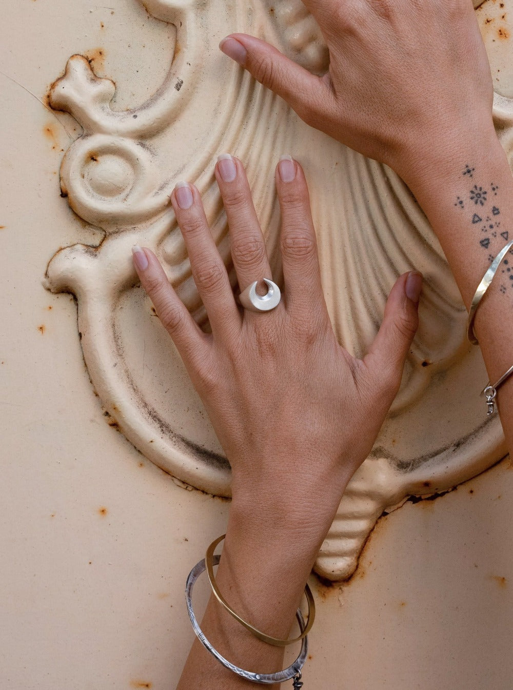 A silver signet ring with a brushed finish, featuring a crescent moon design.