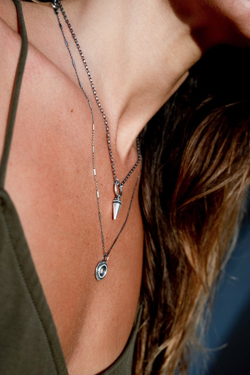 A silver necklace with a pendant featuring a stylized sun and moon design
