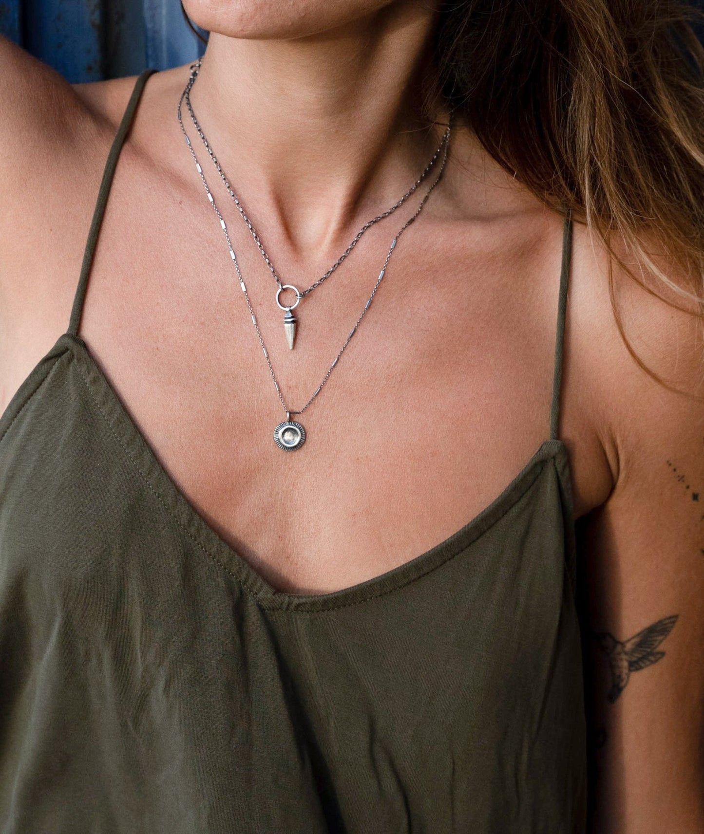 A silver necklace with a pendant featuring a stylized sun and moon design