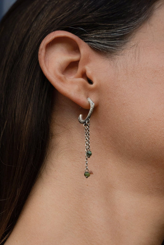 A pair of sterling silver oxidized and brushed finish earrings with turquoise drops and a chain design.