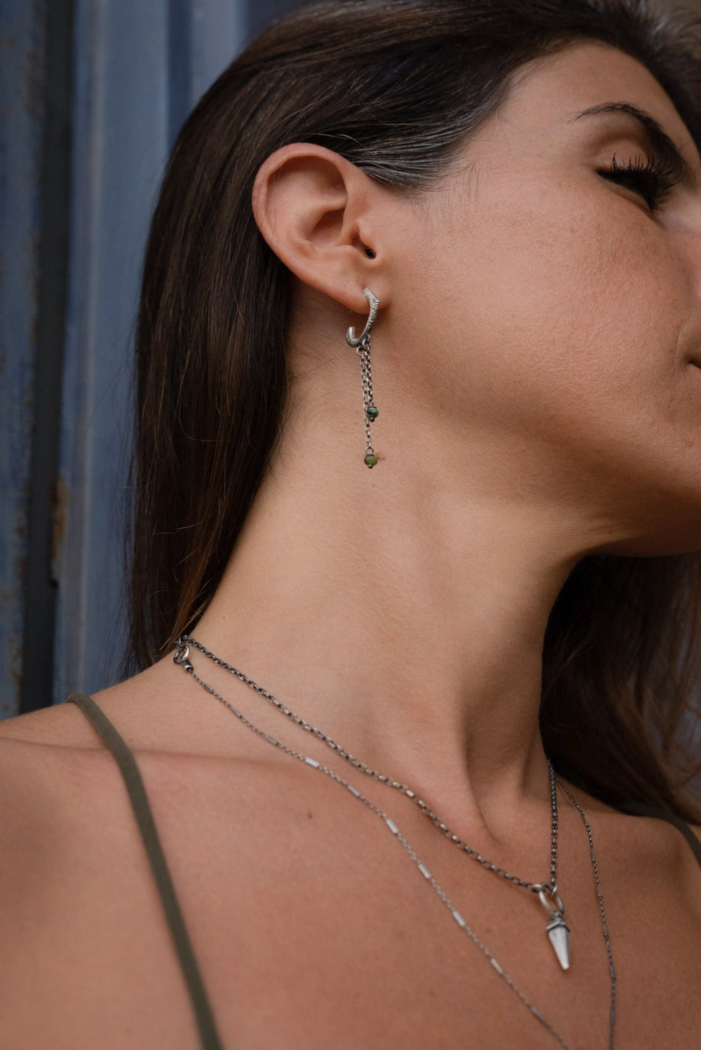 A pair of sterling silver oxidized and brushed finish earrings with turquoise drops and a chain design.