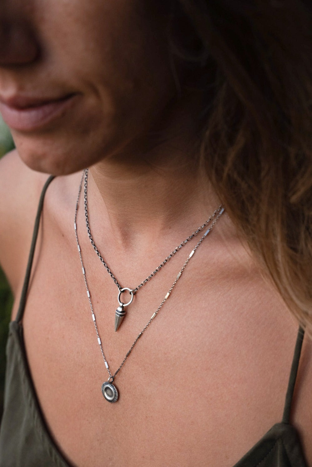 A sterling silver pendulum necklace with a brushed finish and a chain loop at the top.