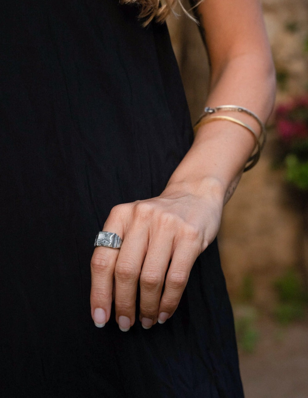 A silver ring with an oxidized and brushed finish, featuring an engraved design inspired by Florentine art, including figures and architectural elements.