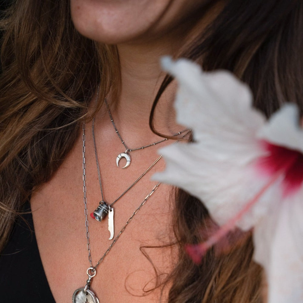 A silver necklace with a crescent-moon pendant and chain.