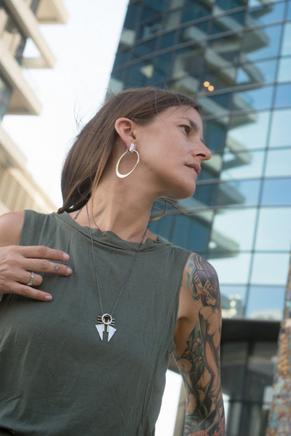 A necklace with a geometric silver pendant featuring a combination of brushed and oxidized finishes, attached to a chain.