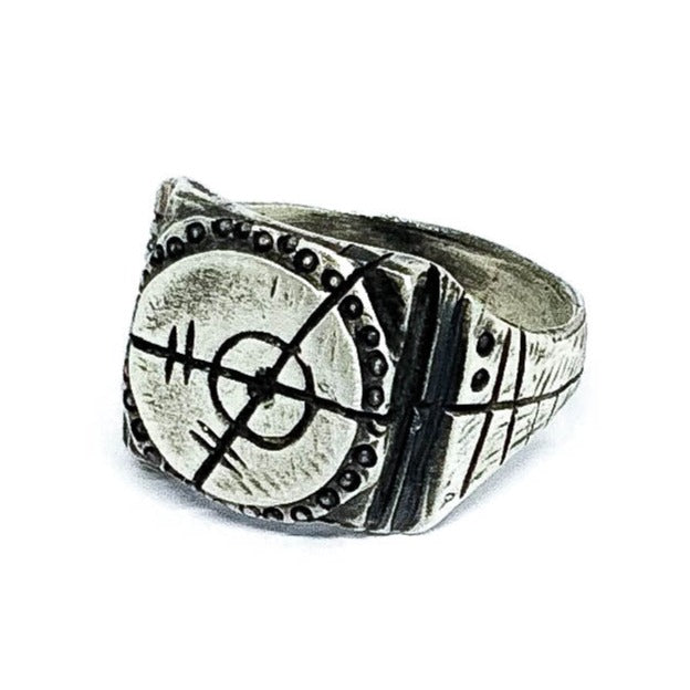 A silver ring with an oxidized and brushed finish, featuring a target design and ornamental details.