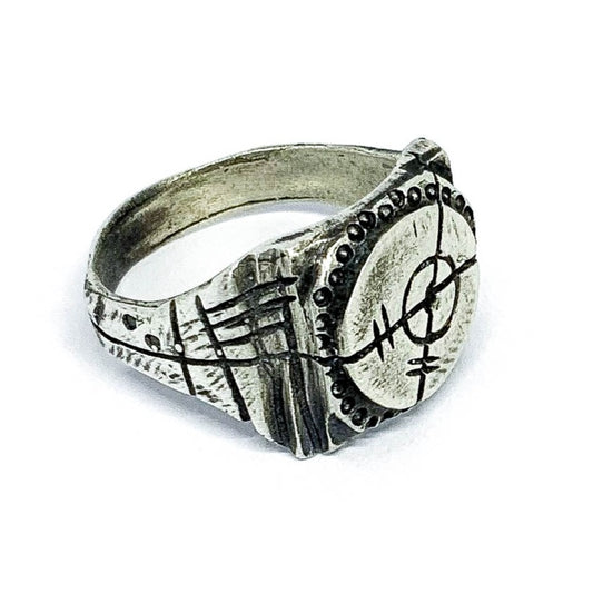 A silver ring with an oxidized and brushed finish, featuring a target design and ornamental details.