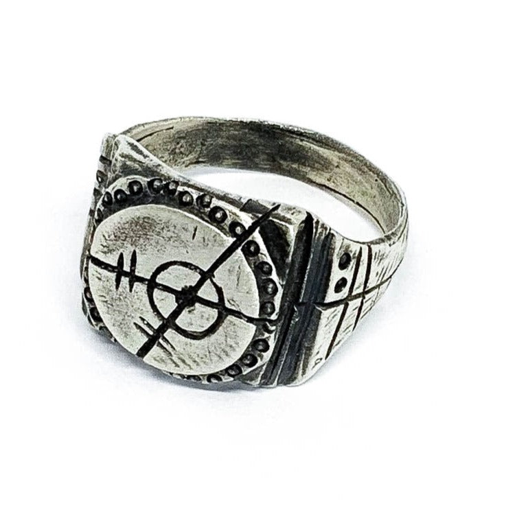 A silver ring with an oxidized and brushed finish, featuring a target design and ornamental details.
