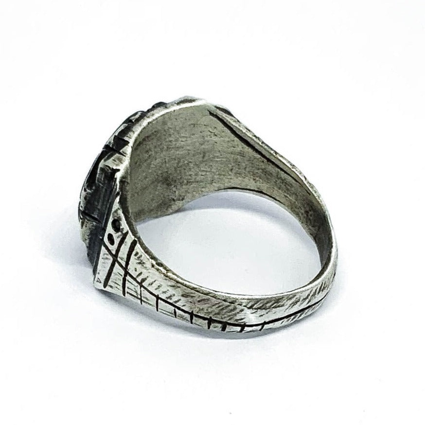 A silver ring with an oxidized and brushed finish, featuring a target design and ornamental details.