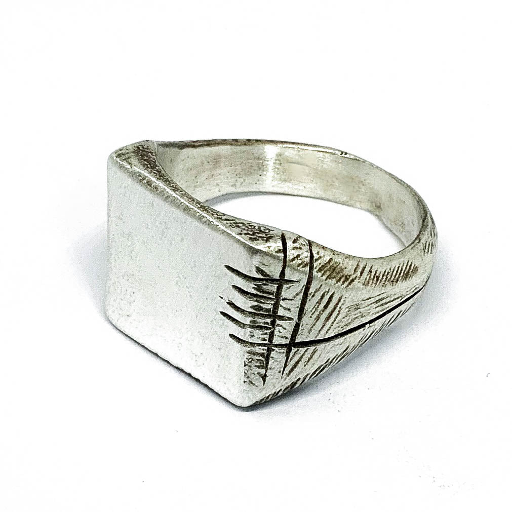 A silver carved memories ring with a textured and embossed pattern, displayed on a white background.