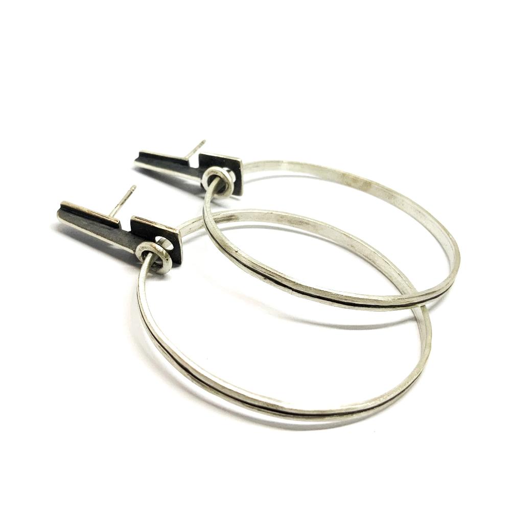 A pair of silver oxidized and brushed finish earrings with a geometric design, displayed against a white background.