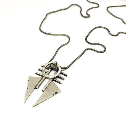 A sterling silver necklace with a pendant featuring two triangles and a circular ornament, with a brushed and oxidized finish.