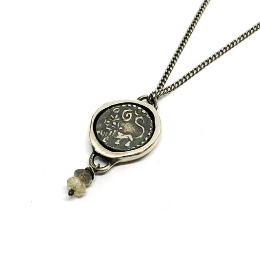 A silver necklace with a pendant featuring an ancient Hindu coin design with the figure of Hanuman- Monkey god, accompanied by two tiny labradorite stones.