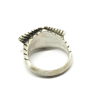 A silver ring with an oxidized and brushed finish, featuring a textured design on the top part.