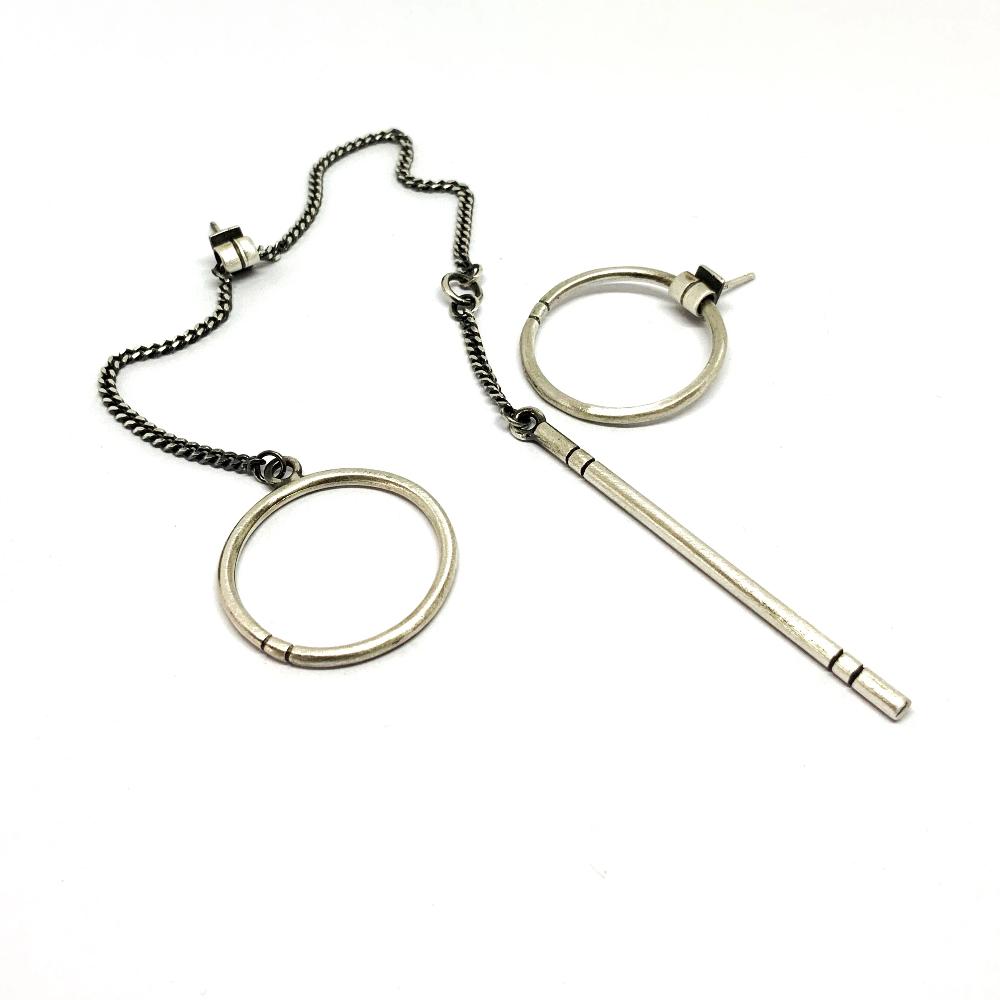 A pair of silver hoop earrings, one with a dangling tube design and the other with a chain hoop design, both made of sterling silver with a brushed finish.