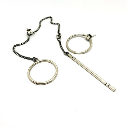 A pair of silver hoop earrings, one with a dangling tube design and the other with a chain hoop design, both made of sterling silver with a brushed finish.